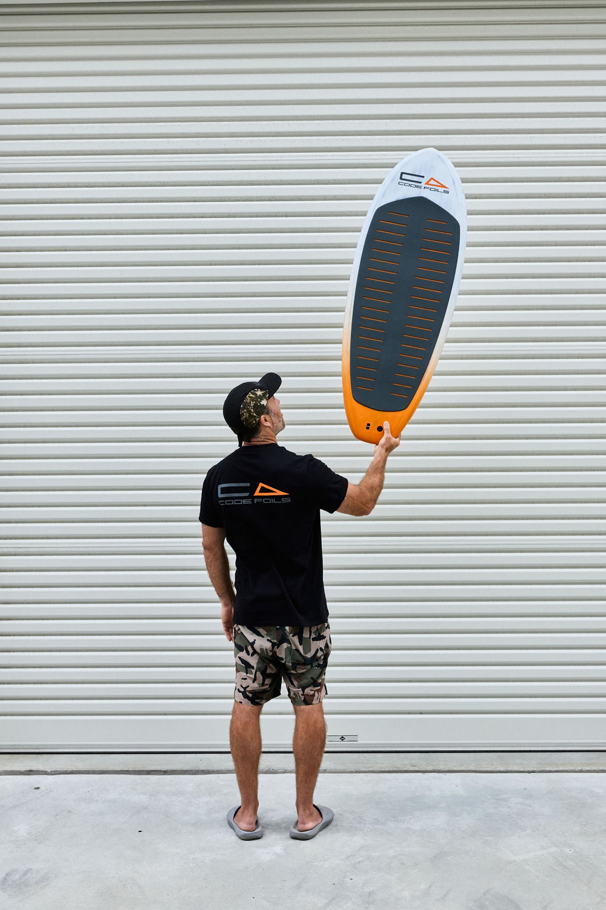 Code Foils Prone board held overhead with the deck pad visible