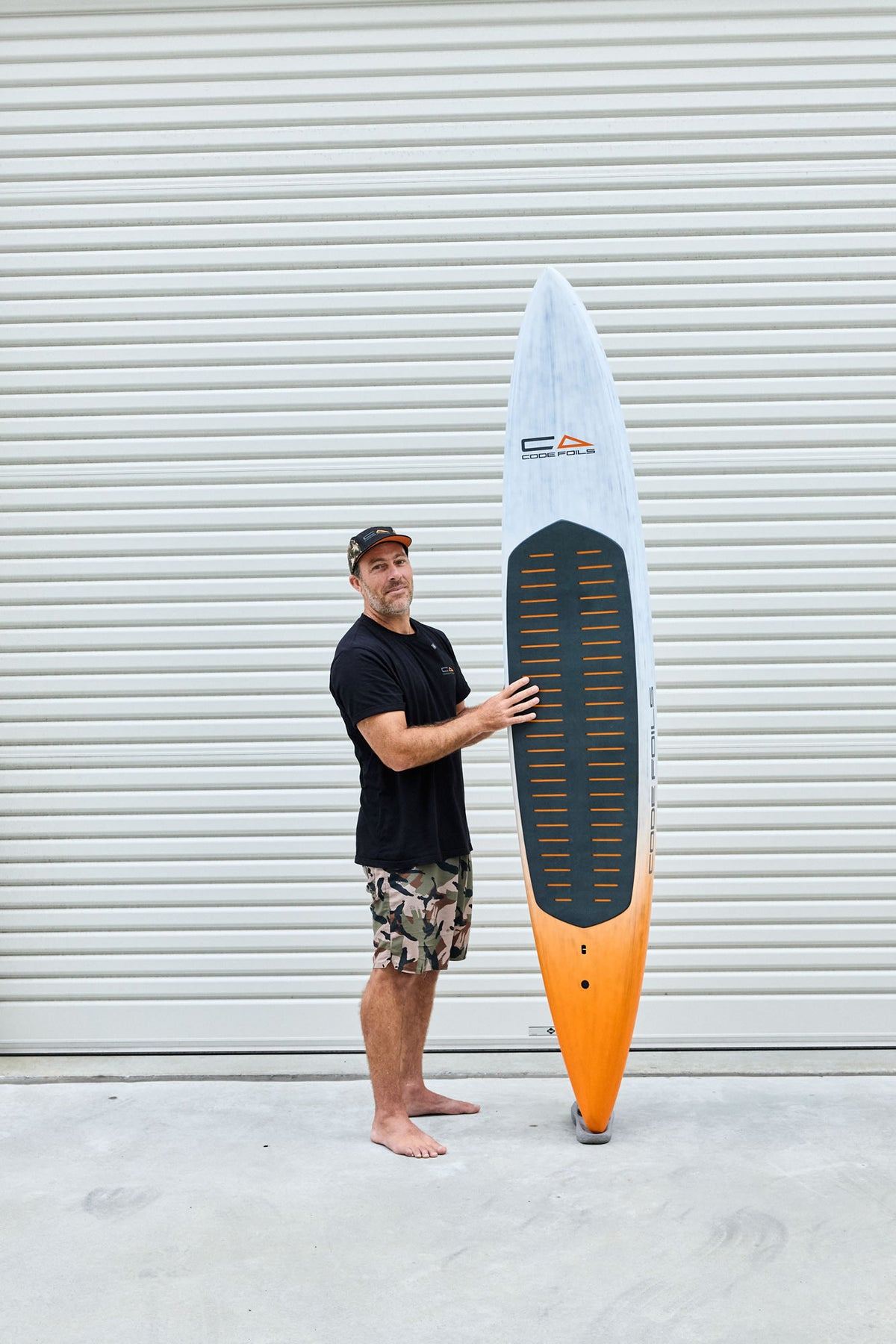 Code Foils Downwind SUP board held upright beside a rider for scale