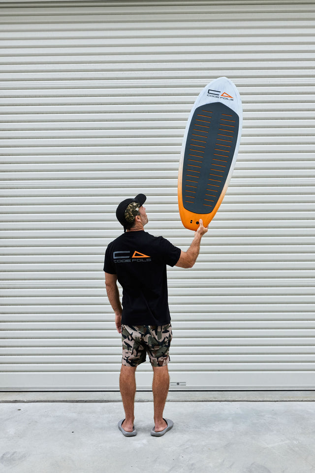 Code Foils Prone board held overhead with the deck pad visible